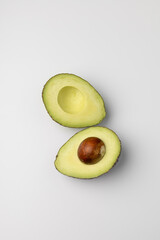Two halves of fresh avocado on white background