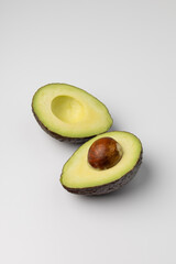 Two halves of fresh avocado on white background