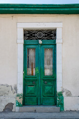 Green old wooden front door with metal grates in stone wall