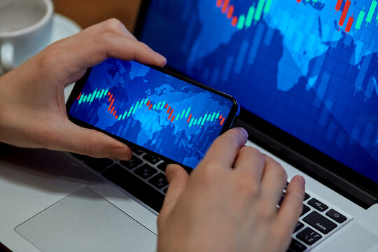 Trading. Businessman investor analyst using mobile phone analytics to analyze cryptocurrency financial market, trade data index chart graph on smartphone and laptop screen. close up
