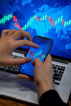 Trading. Businessman investor analyst using mobile phone analytics to analyze cryptocurrency financial market, trade data index chart graph on smartphone and laptop screen. close up