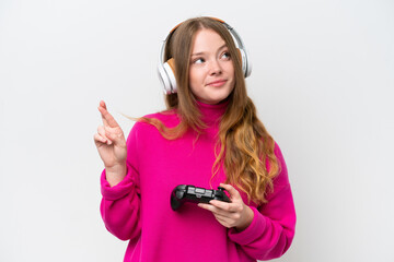 Young pretty woman playing with a video game controller isolated on white background with fingers crossing and wishing the best