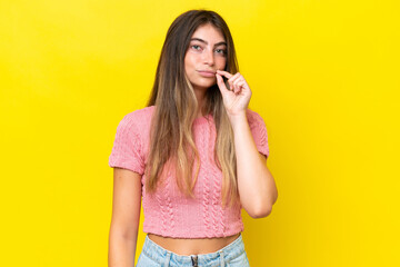 Young caucasian woman isolated on yellow background showing a sign of silence gesture