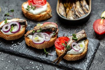 opened cans with sprats, with herbs, lemon and onion. Food recipe background. Close up