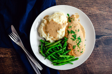 Chicken Breast Served with Green Beans, Mashed Potatoes, and Garlic Gravy: Chicken cutlet topped with creamy garlic sauce served with vegetables