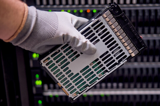 A hard disk for a raid in the hands of a man at a data storage server, close-up