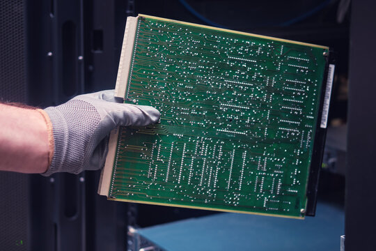 Computer circuit board in the hands of a man at the server for data storage, close-up