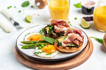 Traditional full English breakfast with grilled bun with spinach and cheese, asparagus, jamon, ham,...
