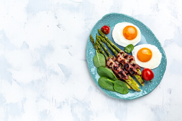 Ketogenic diet. Keto brunch breakfast. fried eggs, asparagus wrapped in bacon, ham, tomatoes and salad. Long banner format. top view