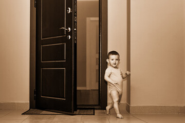 Toddler baby leaves the open door of the apartment. Child boy runs away from home. Kid age one year
