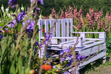 Creative purple bench made of wooden pallets surrounded be seasonal autumn flowers. Selective focus.
