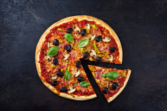 Traditionelle italienische Pizza prosciutto e funghi mit Schinken, Pilzen und Mozzarella serviert als Draufsicht auf einem alten rustikalen Board mit Textfreiraum