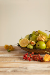 Still life:various assorted fruits (grape, apple, pear,lemon, lime,rowan, physalis) copper plate,isolated on the wooden table background with soft shadow,healthy fresh organic food.Vertical,copy space