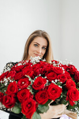 Charming young woman with a huge bouquet of red roses. Gift for birthday or valentine's day. Engagement and signs of love