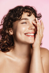 Beauty face. Smiling curly teen girl touching healthy skin portrait. Beautiful happy woman model...