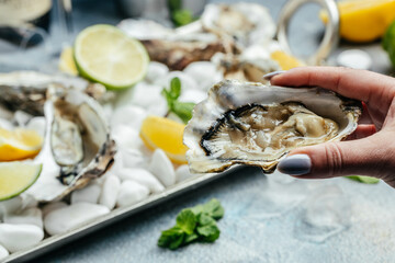 Fototapeta Fresh oysters on ice with lemon. Healthy food, gourmet food. Oyster dinner in restaurant obraz