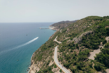 Aerial view of drone about road between green mountain with road and blue mediterranean sea