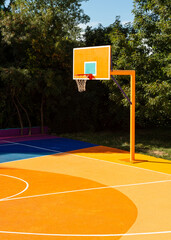 Orange basketball backboard on colorful outdoor basketball court. © youngoggo