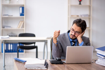 Young male employee unhappy with excessive work in the office