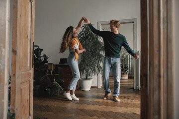 Fototapeta na wymiar Full length of carefree young couple dancing at home together