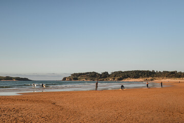 group of surfers on the beach as they prepare to enter the water for surfing during a surf and travel week experience in Somo, Cantabria (Spain)