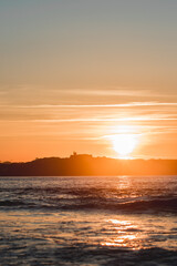 Naklejka premium Spectacular panoramic view of a castle on the horizon on the mountain over the sea at sunset during a surf and travel week experience in Somo, Cantabria (Spain)