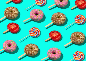 Pattern concept with pink and chocolate donuts on a stick, a red slice of tomato and lollipop. Creative party idea on green background.