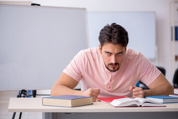 Young male student preparing for exams in the classroom