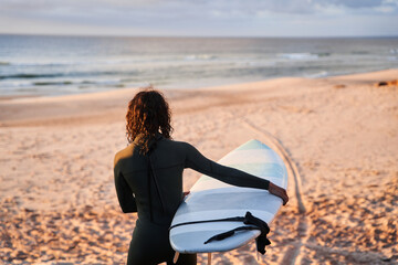 Fototapeta na wymiar Beach surfer woman going through sandy beach with surf board