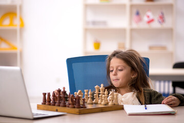Young little girl playing chess at home