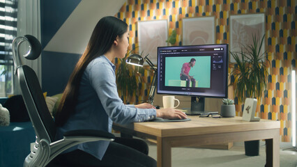 Asian woman editing photo in photoshop for customer on personal computer while sitting at the table at home office and working remotely