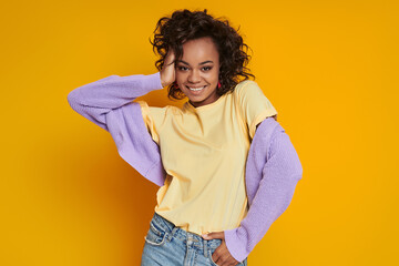 Attractive African woman smiling while standing against yellow background