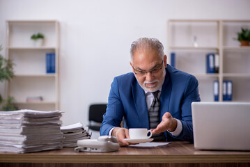 Obraz na płótnie Canvas Old male employee drinking coffee during break