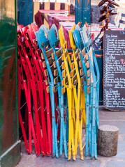 Fototapeta premium Colorful chairs lean against a bistro wall in Paris France. A menu handwritten in chalk on a blackboard is out of focus in the background.