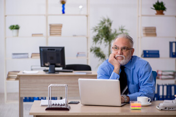 Obraz premium Old male employee working in the office