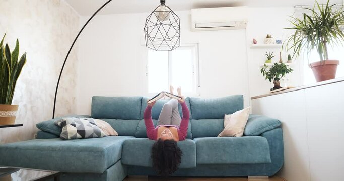 woman lying on her back on the sofa reading a book