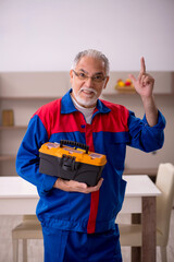 Old male carpenter working indoors