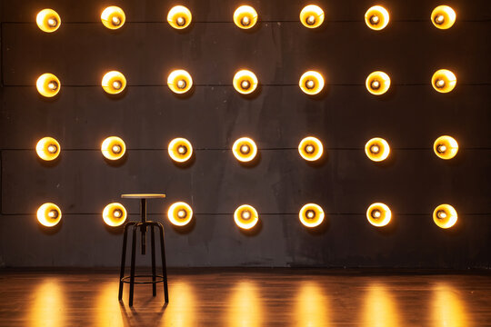 iron chair on the background of a wall with spotlights. photo zone with incandescent lamps on the wall. garland of yellow lamps on a dark wall. photo zone for a male photo shoot