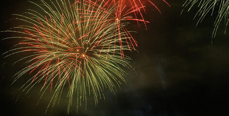 Fototapeta premium Fogo de artifício a rebentar no céu com duas cores diferentes, verde, vermelha, festival de pirotecnia 