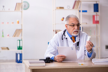 Old male doctor working in the clinic