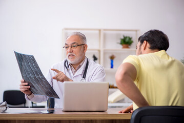 Obraz premium Young male doctor visiting old male doctor radiologist