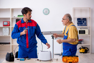 Two male repairmen working at workshop