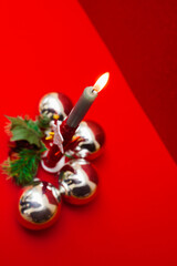 christmas postcard with burning candle decorated with christmas tree balls, stars and holly.