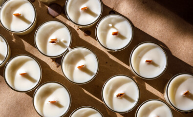 A row of scented candles illuminated by the bright sun stands on the table.