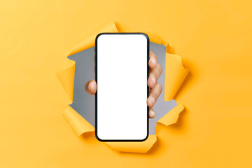 Male hand showing smartphone with blank white mock up screen through hole in ripped orange paper...