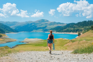Young European woman walks towards an alpine lake to have a snack during a walk in her healthy life.