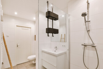 Sinks with mirrors and shower box with glass door in modern bathroom with white tiled walls