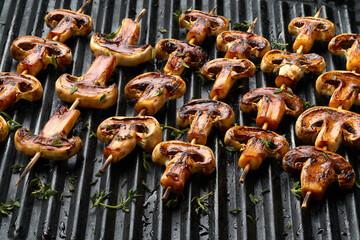 Cooking mushrooms on the grill. Champignon mushrooms are grilled on skewers on the grill,selective focus.