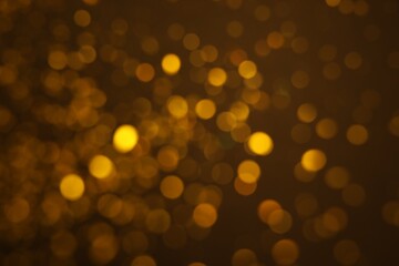 Obraz premium Blurred view of golden glitter on dark background. Bokeh effect