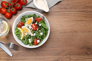 Delicious salad with boiled egg, tomatoes and cheese served on wooden table, flat lay. Space for text